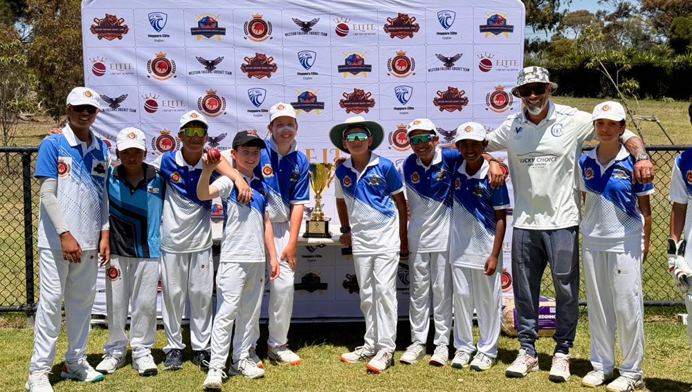 Northern Warriors players and their coach in front of the league backdrop, the trophy between them.