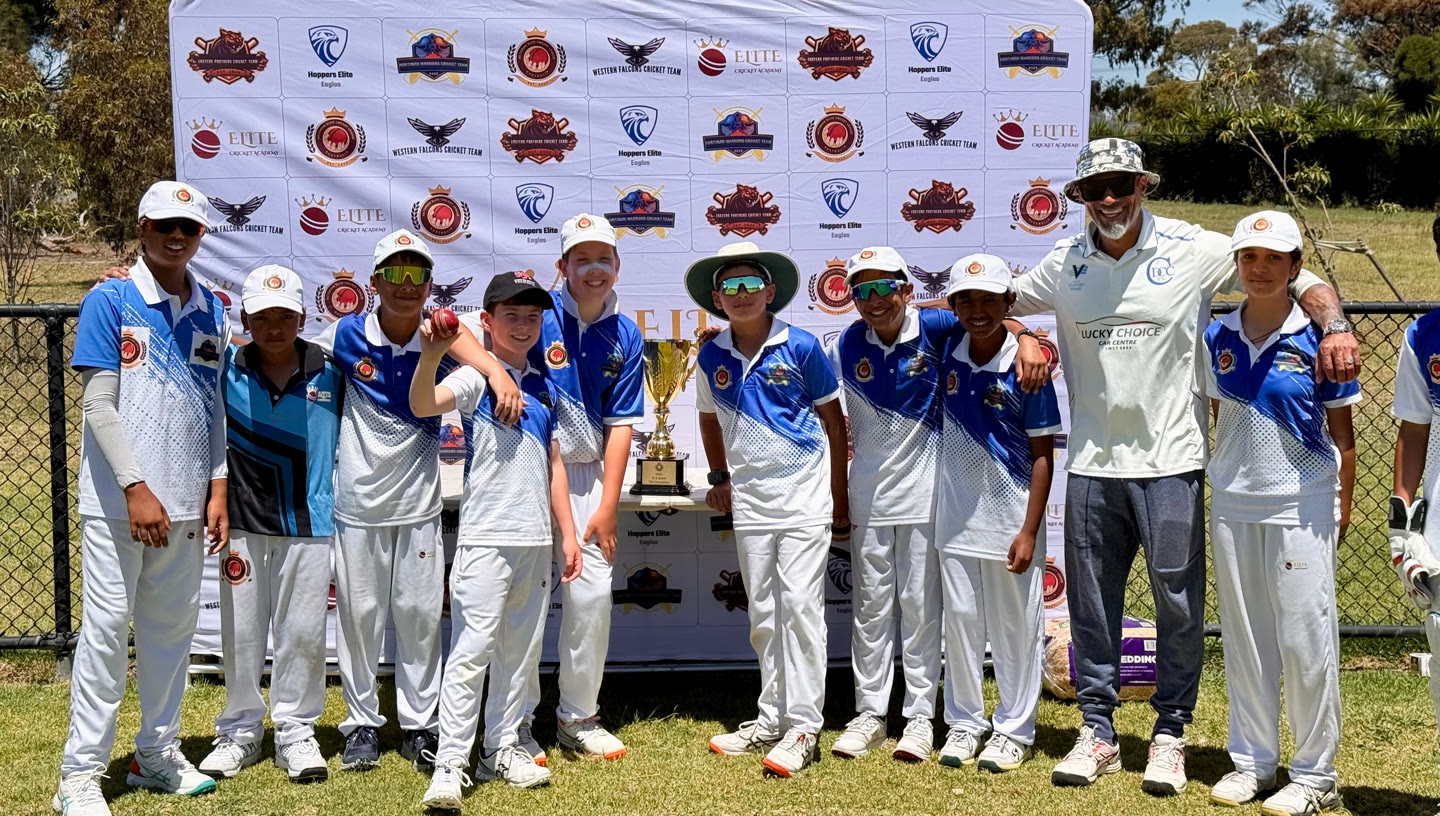 Northern Warriors players and their coach in front of the league backdrop, the trophy between them.
